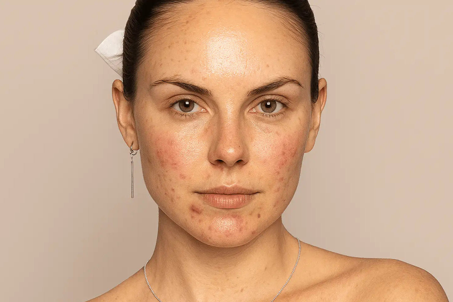 Woman with a neutral expression on a beige background